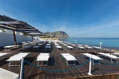 a deck with white lounge chairs and the ocean at La Marsa Vacances in Mondello