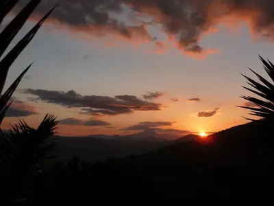 a sunset with the sun setting over the mountains at Villa della Mimosa in Alia