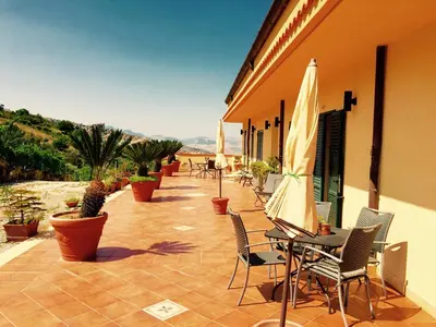a patio with chairs and a table with an umbrella at Villa della Mimosa in Alia