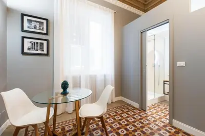 a dining room with a glass table and white chairs at casa mo room and suite in Palermo