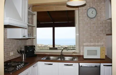 a kitchen with a sink and a clock on the wall at Villa Ibiscus in Mandra Capreria
