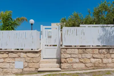 a fence with a white gate and stairs at Villa con piscina Alcamo Marina in Alcamo