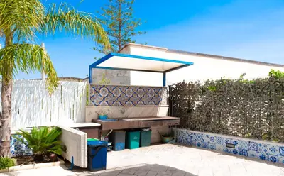 a bench in front of a fence with a fountain at Villa con piscina Alcamo Marina in Alcamo