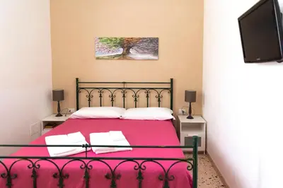 a bedroom with a bed with a pink blanket and a tv at Villa con piscina Alcamo Marina in Alcamo