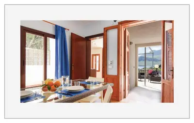 a dining room with a table and a view of a house at Villetta SanVito - Sunrise & Sunset in San Vito lo Capo