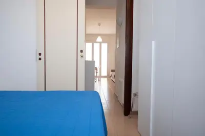a bedroom with a blue bed and a hallway at Appartamento Conturrana Sul Mare in San Vito lo Capo