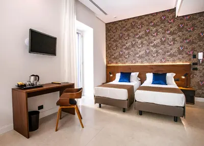 a bedroom with two beds and a desk and a tv at Palazzo Sovrana Serviced Luxury Apartments in Palermo
