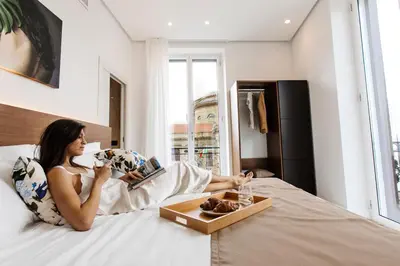 a woman laying on a bed with a tray of food at Palazzo Sovrana Serviced Luxury Apartments in Palermo