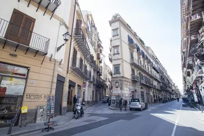 a city street with buildings and a man on a motorcycle at B&B del Parlamento in Palermo