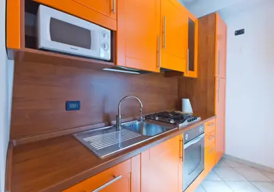 a kitchen with orange cabinets and a sink and a microwave at Palazzo Gallo in Palermo