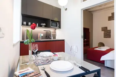 a small kitchen with a table with a red couch at Dietro la Cattedrale in Palermo