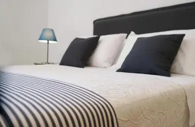 a bed with black and white pillows and a lamp at T-home / Stylish apartment Palermo center in Palermo