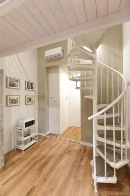 a white spiral staircase in a room with wooden floors at Maison Cutò in Palermo