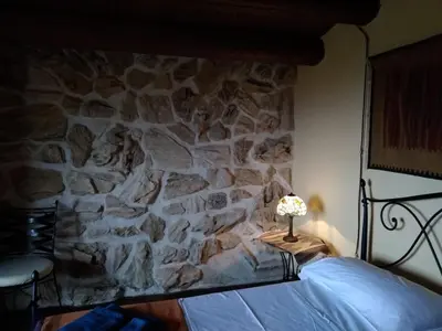 a bedroom with a stone wall with a bed and a lamp at Ziba Villa Siciliana con piscina e vista panoramica sul mare in Borgetto