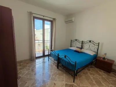 a bedroom with a blue bed and a large window at Katia appartamenti in San Vito lo Capo