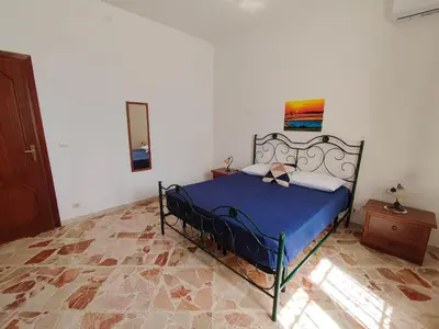 a bedroom with a bed with a blue comforter at Katia appartamenti in San Vito lo Capo
