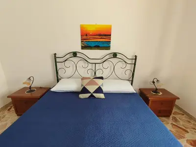 a bedroom with a bed with a blue blanket and two night stands at Katia appartamenti in San Vito lo Capo