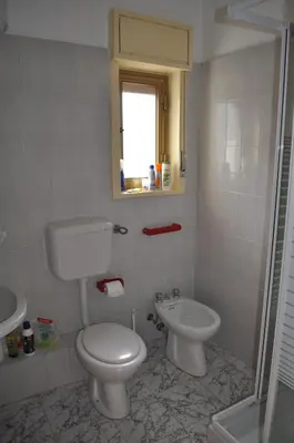 a white bathroom with a toilet and a sink at Summerhouse Sagana in Monreale