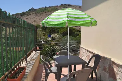 a table and chairs with an umbrella on a balcony at Summerhouse Sagana in Monreale