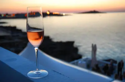 a glass of wine sitting on a ledge near the water at Casa sul mare in Isola delle Femmine