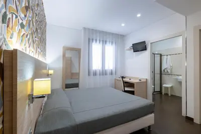 a bedroom with a bed and a desk and a mirror at Alaba Hotel in San Vito lo Capo