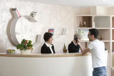 a man standing in front of a counter with two women at Alaba Hotel in San Vito lo Capo