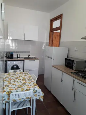 a white kitchen with a table and a stove at Casa BabbaLuciana in Mondello