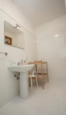 a white bathroom with a sink and a mirror at Casa BabbaLuciana in Mondello