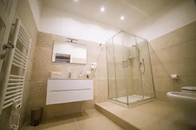 a bathroom with a glass shower and a sink at B&B Opera dei Pupi in Palermo