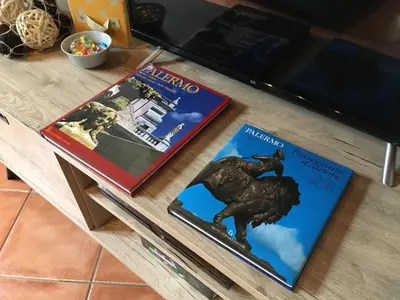 two books sitting on a table next to a television at Palazzo Rea in Palermo