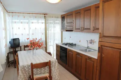 a kitchen with wooden cabinets and a table with a sink at case vacanze Rosy in San Vito lo Capo