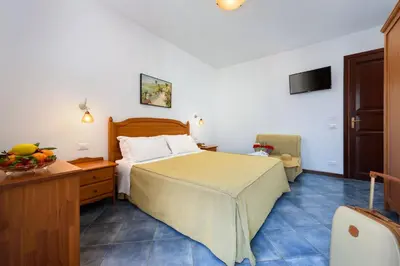 a hotel room with a bed and a chair at La Meridiana Hotel in San Vito lo Capo