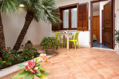 a patio with a table and a palm tree at La Meridiana Hotel in San Vito lo Capo