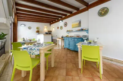 a kitchen with wooden tables and green chairs at La Meridiana Hotel in San Vito lo Capo