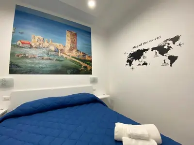 a bedroom with a blue bed and a painting on the wall at IN CENTRO ROOMS Vicino Cefalù SELF-CHEK-IN in Campofelice di Roccella
