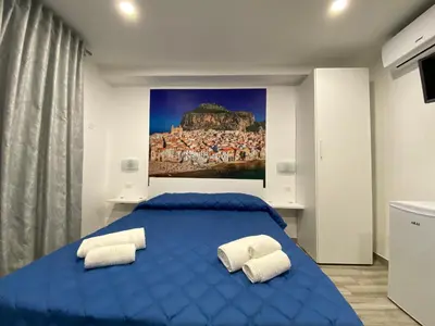 a bedroom with a blue bed with two white pillows at IN CENTRO ROOMS Vicino Cefalù SELF-CHEK-IN in Campofelice di Roccella