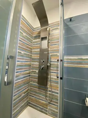 a shower in a bathroom with ailed wall at IN CENTRO ROOMS Vicino Cefalù SELF-CHEK-IN in Campofelice di Roccella