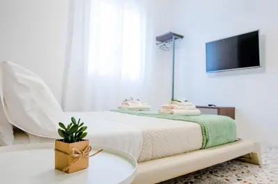 a white bedroom with a bed and a tv at CIELO D' ALCAMO Palazzo Adamo in Alcamo