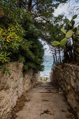 an alley with a stone wall and the ocean at Casa Vela Bianca Mondello Addaura in Palermo