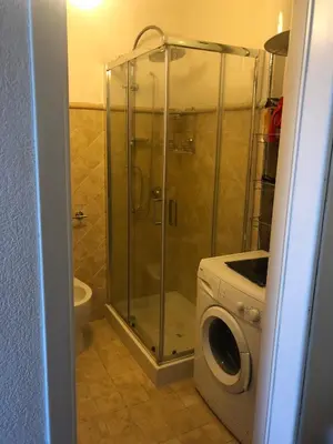 a bathroom with a shower and a washing machine at Casa Vela Bianca Mondello Addaura in Palermo