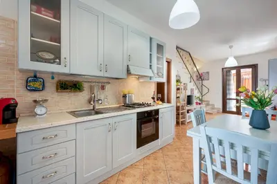 a kitchen with white cabinets and a sink and a table at Carlottas Home in San Vito lo Capo