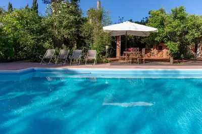 a swimming pool with chairs and an umbrella at Il Giardino di Michela by DomuSicily in Mondello