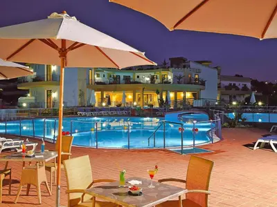 a pool with tables and umbrellas next to a building at Residence in Sicily near Himera & Madonie Park in Buonfornello