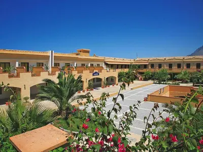 a large building with a parking lot with flowers at Residence in Sicily near Himera & Madonie Park in Buonfornello