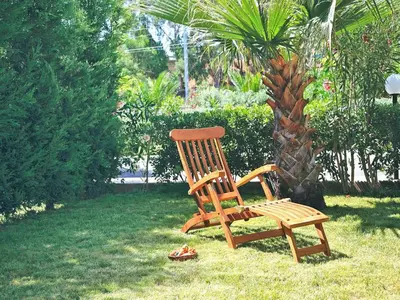 a wooden bench sitting in the grass next to a palm tree at Residence in Sicily near Himera & Madonie Park in Buonfornello