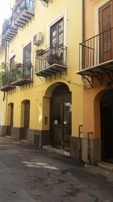 a yellow building with balconies and doors on a street at Casa Ruggiero in Palermo