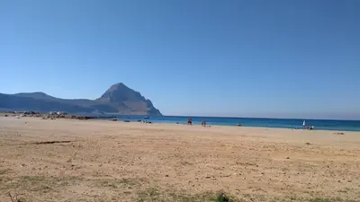 a beach with people on it with a mountain in the background at Villetta con giardino Mandarino Macari in Macari