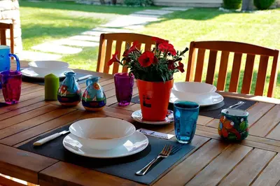 a wooden table with plates and bowls and a vase with flowers at Villa Araucaria in Partinico