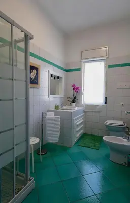 a green and white bathroom with a sink and toilet at Villa Araucaria in Partinico