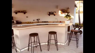 a kitchen with a counter with stools around it at Villa Araucaria in Partinico
